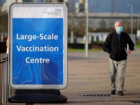 A man walks past a sign outside the mass vaccination centre at the Totally Wicked Stadium, in St Helens, Merseyside, Britain, January 18, 2021.