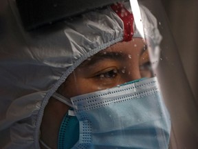 FILE: Beads of sweat gather on the face shield of a healthcare worker.