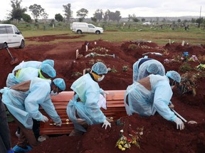Funeral workers wearing personal protective equipment carry a casket during the burial of a COVID-19 victim, amid a nationwide coronavirus disease (COVID-19) lockdown, at the Olifantsvlei cemetery, south-west of Joburg, South Africa January 6, 2021.