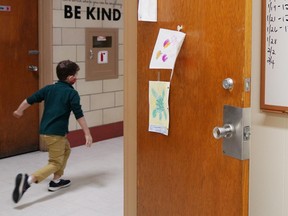 A child runs by the Principal's office where the COVID-19 testing kits needed by date are listed on a white board at South Boston Catholic Academy in Boston, Massachusetts, U.S., January 28, 2021.  REUTERS/Allison Dinner ORG XMIT: GGG-BOS01