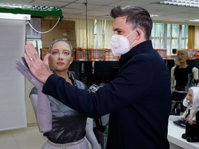 Founder and Chief Executive Officer (CEO) of Hanson Robotics, David Hanson gives a high-five to humanoid robot Sophia at the company's lab in Hong Kong, China January 12, 2021.