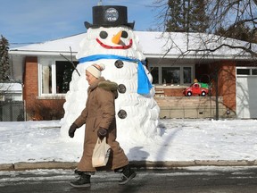 Saidi Rashed walks past a giant happy new year snowman on Holt Crescent in Ottawa Wednesday Jan 6, 2021.  The snowman is about 15feet tall and 6 feet wide.