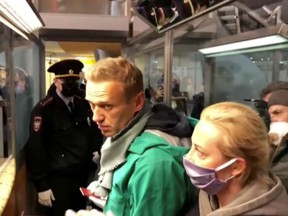 A still image taken from video footage shows law enforcement officers speaking with Russian opposition leader Alexei Navalny before leading him away at Sheremetyevo airport in Moscow, Russia January 17, 2021.
