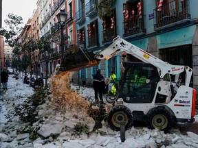 An excavator of the Madrid City Council removes snow and ice in the centre of Madrid, Spain, January 13, 2021.