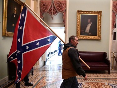 A supporter of President Donald Trump carries a Conferderate battle on the second floor of the U.S. Capitol near the entrance to the Senate after breaching security defenses, in Washington, U.S., January 6, 2021.