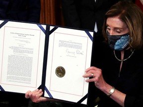 FILE PHOTO: U.S. House Speaker Nancy Pelosi (D-CA) shows the article of impeachment against U.S. President Donald Trump after signing it in an engrossment ceremony, at the U.S. Capitol in Washington January 13, 2021.