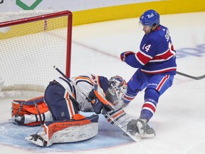 Oilers goalie Mike Smith covers up loose puck under pressure from Canadiens' Nick Suzuki during first period Thursday night at the Bell Centre. Smith made 31 saves for the shutout.