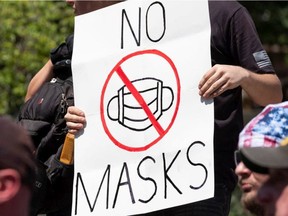 FILE: An anti-mask protestor holds up a sign.