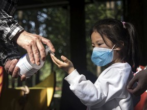 FILE: An employee gives out hand sanitizer to a young girl.