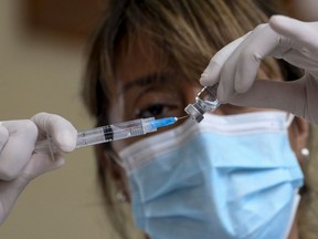 SANTIAGO, CHILE - FEBRUARY 16: A health worker holds a syringe and a glass vial with a COVID-19 vaccine during vaccination to teachers at Abdon Cifuentes on February 16, 2021 in Santiago, Chile.