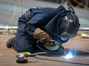 FILE: A construction worker welds metal on a ship.