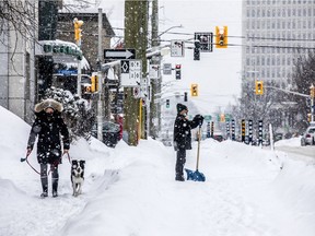 Ottawa was hit with heavy wet snow that blanket the capital Saturday Feb. 27, 2021. A man crosses O'Connor Street with a shovel Saturday as the heavy snowfall came down.