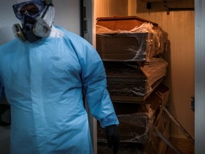 A funeral worker wearing a protection suit stands next to sealed caskets of Covid-19 victims placed in the refrigeration room at a funerary parlor in Amadora, in the outskirts of Lisbon, on January 29, 2021.