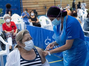 A healthcare worker administers a dose of the Chinese-made COVID-19 vaccine CoronaVac to a teacher at a vaccination centre in Santiago, on February 15, 2021, amid the novel coronavirus pandemic. - Chile on Monday began vaccinating teachers, who were included in the 30% of the population prioritized by the government in the vaccination calendar against COVID-19. After 13 days of mass vaccination in Chile, more 1.8 million people -more than half who are over 71 years old- received at least their first dose, health authorities reported on Saturday.