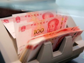 Chinese 100 yuan banknotes are seen in a counting machine while a clerk counts them at a branch of a commercial bank in Beijing, China, March 30, 2016.