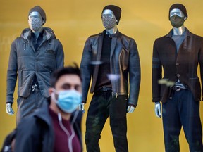 A pedestrian wearing a mask walks through Yorkville with mannequins wearing masks in a clothing store window during the Covid 19 Pandemic, Monday October 5, 2020.