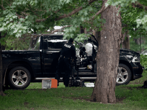 An RCMP police officer looks in the cab of a pickup truck on the grounds of Rideau Hall on July 2. A man who had trafficked in QAnon material was charged with ramming the truck into the grounds of the prime minister.