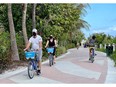 Tourists wear masks as they bike along the beach in Miami in December. The pandemic has separated Canada's "snowbirds" into two camps: those staying home and those heading to Florida no matter the cost, financial or otherwise.