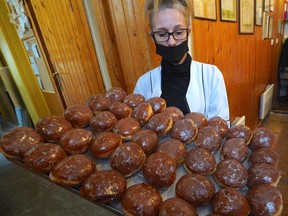 A shop assistant in a popular sweet shop in Warsaw presents jam-filled doughnuts "Paczki" traditionally eaten on the last Thursday of Carnival, the Fat Thursday on February 11, 2021. - Braving sub-zero temperatures and the pandemic, Poles queue for hours to buy traditional Fat Thursday donuts.