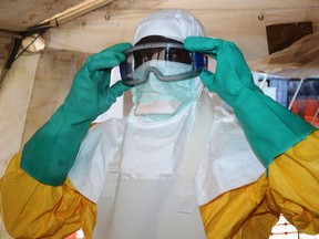 (FILES) This file photo taken on June 28, 2014 shows a member of Doctors Without Borders (MSF) putting on protective gear at the isolation ward of the Donka Hospital in Conakry, where people infected with the Ebola virus are being treated. - Four people have died of Ebola in Guinea, the first resurgence of the haemorrhagic fever in the West African nation since a 2013-2016 epidemic left thousands dead, Health Minister Remy Lamah said on February 13, 2021.