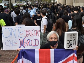 A woman holds up the Union Jack as hundreds of democracy supporters gather outside the West Kowloon court in Hong Kong on March 1, 2021, ahead of court appearances by dozens of dissidents charged with subversion in the largest use yet of Beijing's sweeping new national security law.