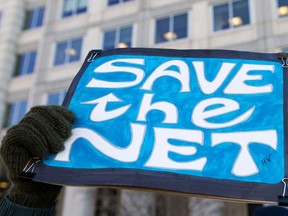 A woman holds a 'Save the Net' protest sign during a demonstration against the proposed repeal of net neutrality outside the Federal Communications Commission headquarters  in Washington, DC on December 13, 2017.