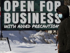 FILE: A pedestrian walks past an open for business sign.