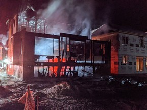 Firefighters engaged in a defensive operation to protect homes on Des Aubrais Crescent from a burning home under construction