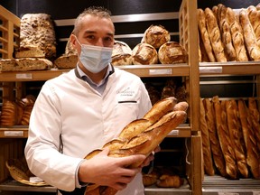 French baker Mickael Reydellet, wearing a protective face mask, poses with freshly-baked baguettes at "La Parisienne" bakery in Paris, France, February 17, 2021.