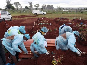 FILE PHOTO: Funeral workers wearing personal protective equipment carry a casket during the burial of a COVID-19 victim at the Olifantsvlei cemetery, south-west of Joburg, South Africa January 6, 2021.