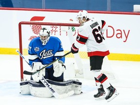 Ottawa Senators forward Evgeni Dadonov deflects the puck in front of Winnipeg Jets goalie Connor Hellebuyck during the third period at Bell MTS Place on Saturday.