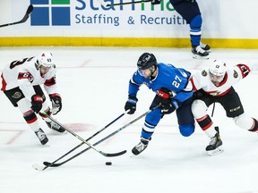 Winnipeg Jets forward Nikolaj Ehlers battles Ottawa Senators forward Nick Paul (right) and forward Evgeni Dadonov (left) for the puck during the first period at Bell MTS Place on Saturday.