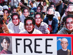 Protesters wearing masks depicting ousted leader Aung San Suu Kyi, flash three-finger salutes as they take part in a protest against the military coup in Yangon, Myanmar, February 28, 2021.