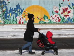 A woman and her child go for a cold weather walk past a warm sunset on York Street in Ottawa.