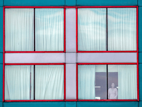 Files: A person looks out of a window at a quarantine hotel.