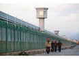 Workers walk by the perimeter fence of what is officially known as a vocational skills education centre in Dabancheng in Xinjiang Uyghur Autonomous Region, China Sept. 4, 2018.  Repression of Muslim minorities by the Beijing government has been likened to genocide.