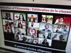 Participants raise their hands to swear the oath to become Canadian citizens during a virtual citizenship ceremony held over livestream due to the COVID-19 pandemic last year.