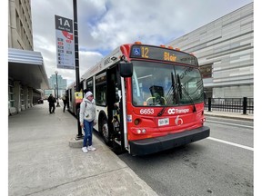 A rider boards an OC Transpo bus in Ottawa. Many buses have been running nearly empty during the pandemic year.