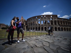 Visitors stand by the Colosseum monument which reopens to the public on June 1, 2020 in Rome.