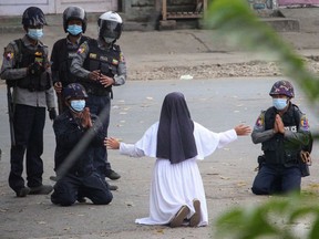 This handout photo taken on March 8, 2021 and released on March 9 by the Myitkyina News Journal shows a nun pleading with police not to harm protesters in Myitkyina in Myanmar's Kachin state, amid a crackdown on demonstrations against the military coup.