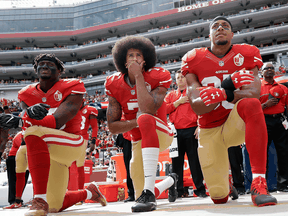 Quarterback Colin Kaepernick and two San Francisco 49er teammates kneel during the national anthem before an NFL football game against the Dallas Cowboys, Oct. 2, 2016.