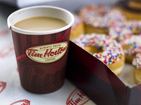 A cup of Tim Hortons Inc. coffee and doughnuts are arranged for a photograph in Toronto, Ontario, Canada, on Wednesday, Aug. 3, 2011.