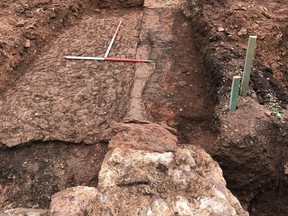 The photo shows a later cobbled floor and in the right-hand foreground the remains of a medieval wall. At the pointed end of the ranging pole is the remains of a medieval fireplace. It is thought the site encompasses part of a hallway and kitchen block.