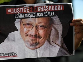 In this file photo taken on Oct. 2, 2020, friends of murdered Saudi journalist Jamal Khashoggi hold posters bearing his picture as they attend an event marking the second-year anniversary of his assassination.
