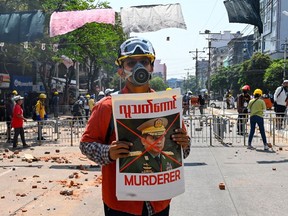 FILE: A protester holds a poster featuring Myanmar armed forces chief Senior General Min Aung Hlaing during a demonstration against the military coup in Yangon on March 9, 2021.