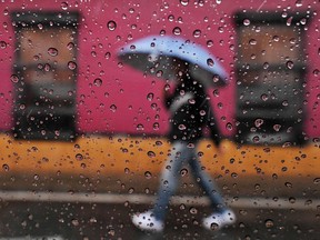 Files: A man walks holding an umbrella.