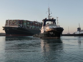 A handout picture released by the Suez Canal Authority on March 29, 2021 shows tugboats pulling the Panama-flagged MV 'Ever Given' (operated by Taiwan-based Evergreen Marine) container ship, a 400-metre- (1,300-foot-)long and 59-metre wide vessel, lodged sideways impeding traffic across Egypt's Suez Canal waterway.