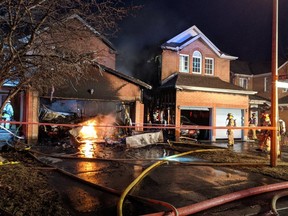 Ottawa Fire Services crews fight a garage fire that spread to a neighbouring residence on Burntwood Avenue, near Nottingham Court, in Barrhaven on the evening of Thursday, March 25, 2021.