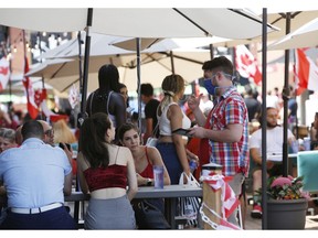 A server wearing a protective mask takes an order at a patio in the ByWard Market on Canada Day, 2020. City council is considering a proposal to keep restaurant patios on city-owned property open until 2 a.m. next summer.