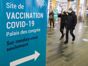People walk past a COVID-19 vaccination clinic Thursday, March 4, 2021 in Montreal.